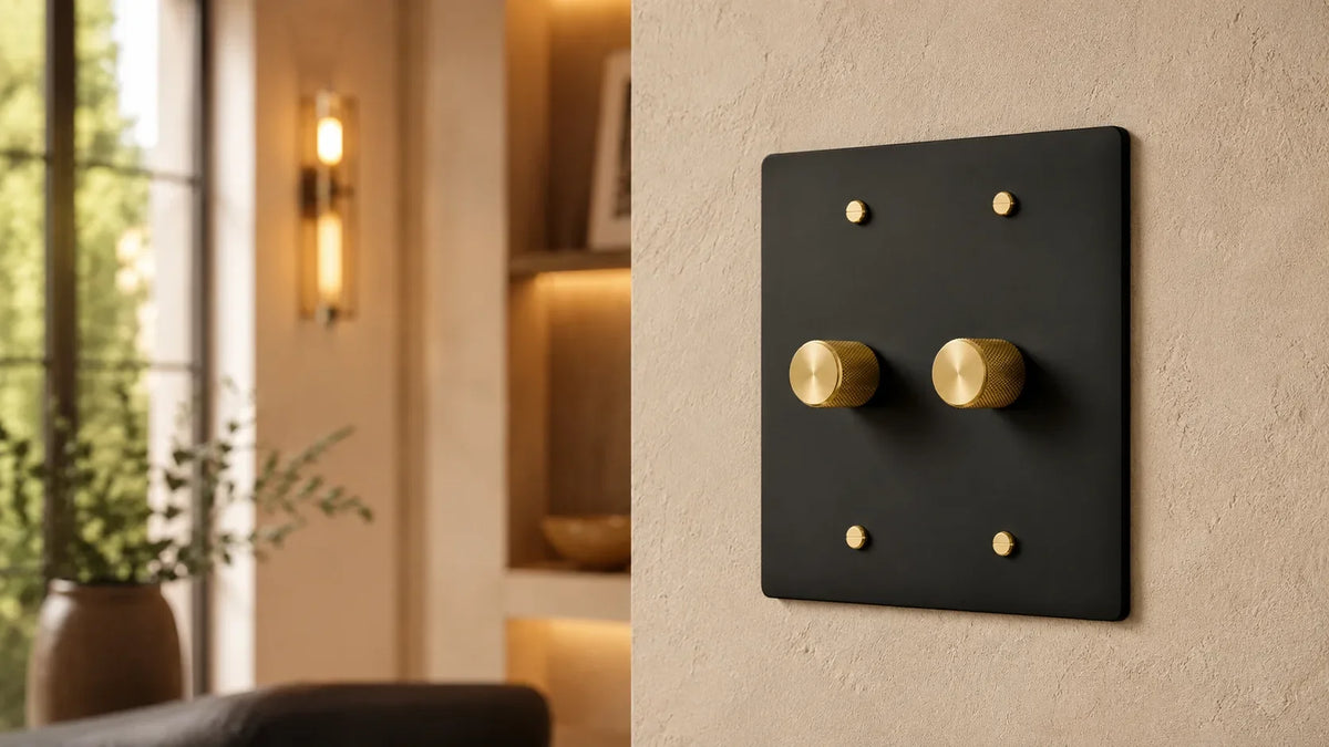 Matte black dimmer switch with brass rotary knobs in a modern interior