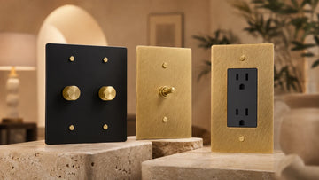 Brass toggle switch, dimmer and electrical outlet displayed in a luxury interior