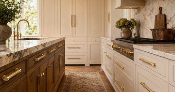 Luxury kitchen with polished brass cabinet hardware, featuring fluted brass pulls and matching round knobs on cream and wood cabinetry.