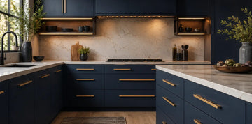 Modern navy kitchen with sleek brass cabinet pulls on drawers and cabinets, paired with light stone countertops and warm ambient lighting.