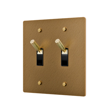 aged brass double toggle switch with black switches on a white background