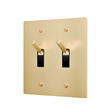Gold double toggle switch with black switches on a white background