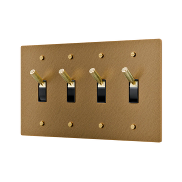Aged brass light switch panel with four black switches on a white background