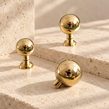 Ball Cabinet Knobs — Polished Brass on warm ivory stone