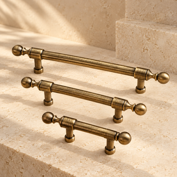 Ball-Foot Spindle Cabinet Pull & Knob — Antique Brass on warm ivory stone