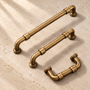 Antique Brass Solid Brass Cabinet Pulls & Knobs — Modern Pipe Design on warm ivory stone