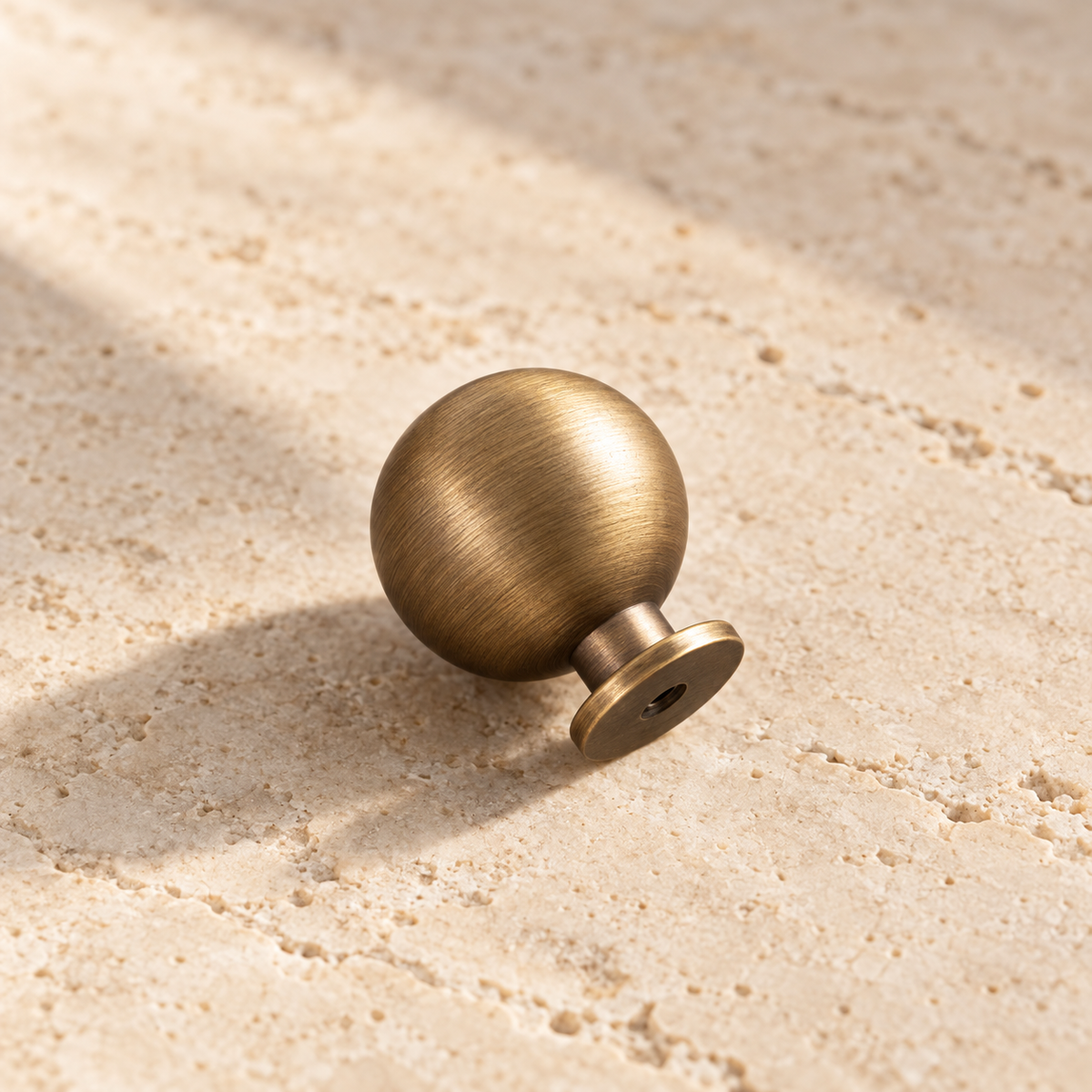 Antique Brass Round Cabinet Knob — Solid Brass on warm ivory stone