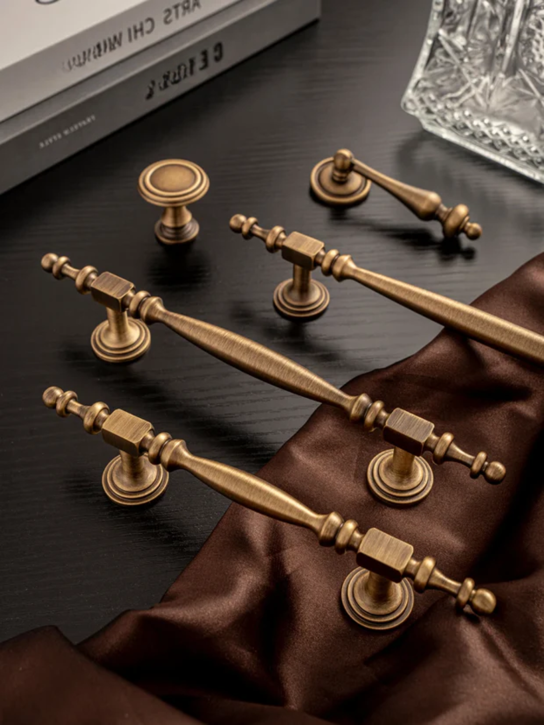 Set of gold cabinet handles on a dark surface with a brown fabric background