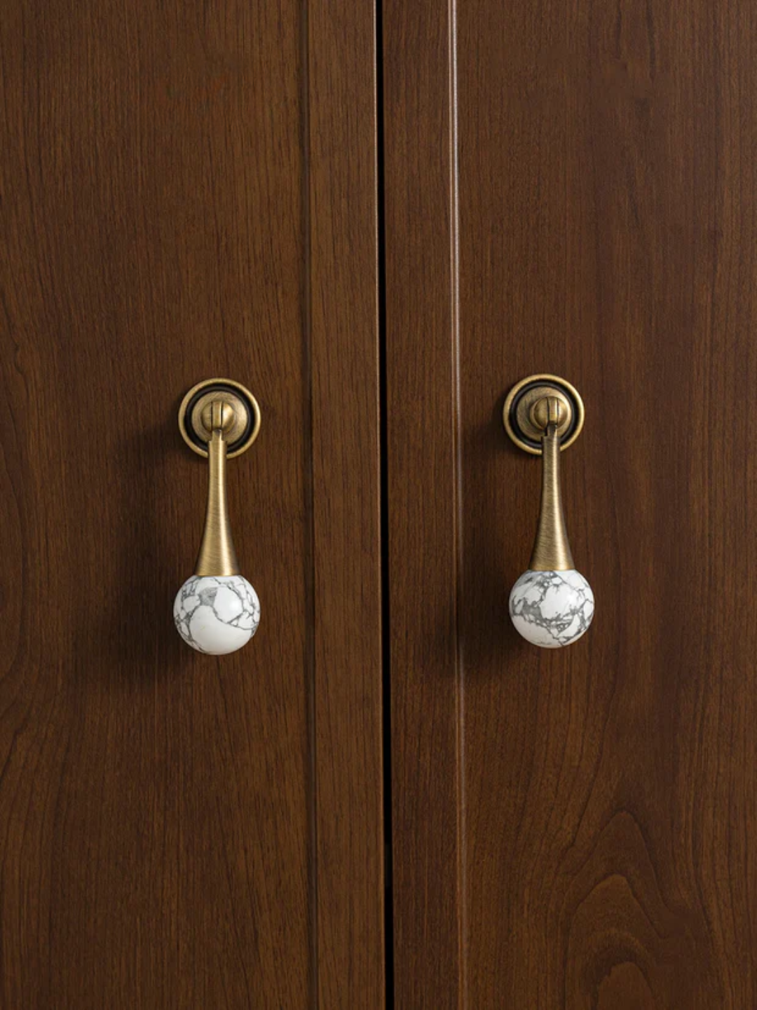Pair of wooden doors with brass handles and marble knobs.