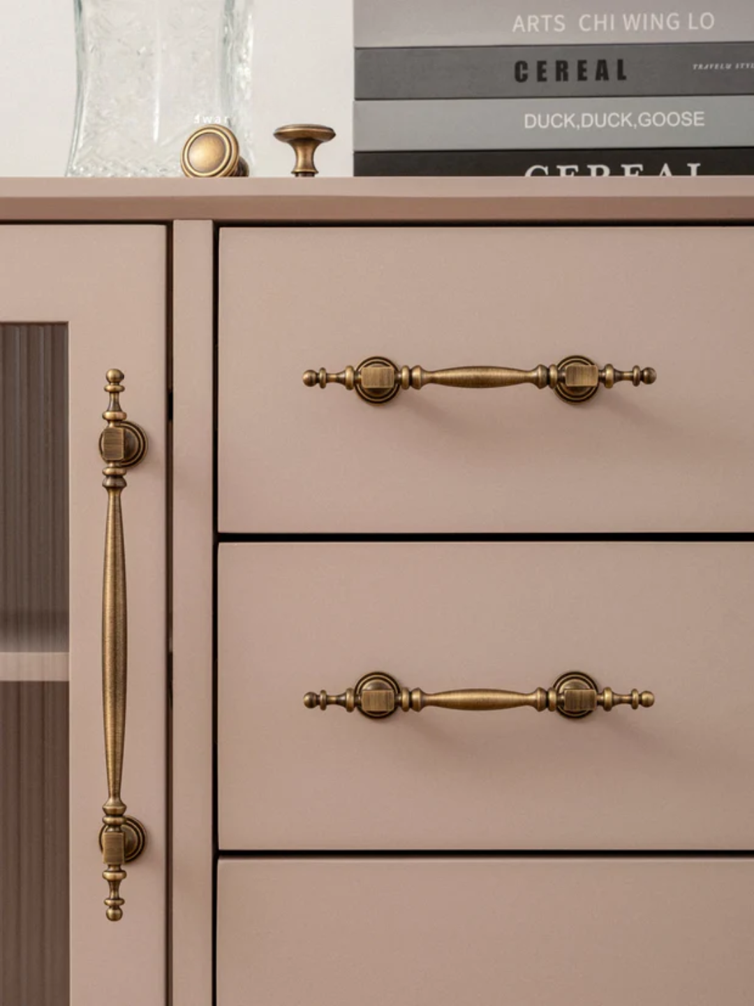 Close-up of a beige cabinet with gold handles and a blurred background.