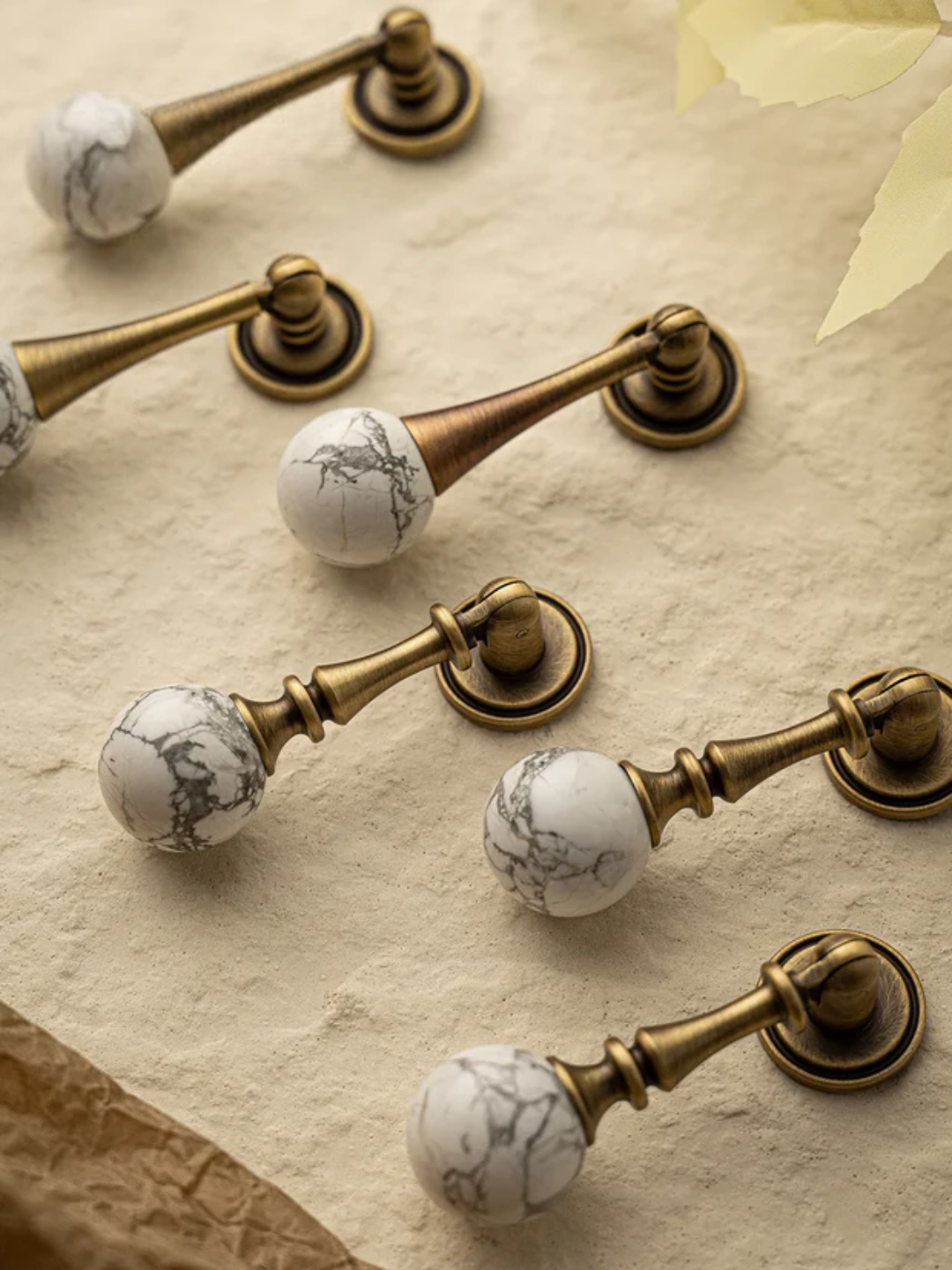 Decorative cabinet knobs with marble and brass design on a textured surface