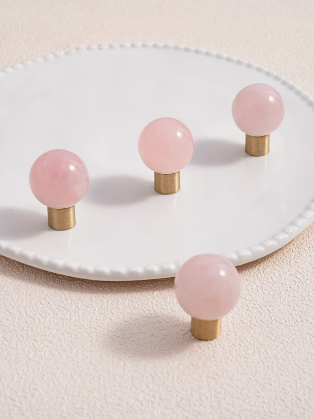 Pink spherical knobs on gold stems on a white plate