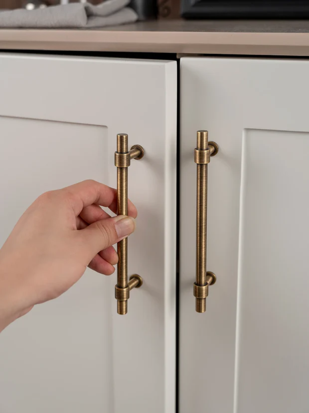 Hand opening a cabinet door with brass handles
