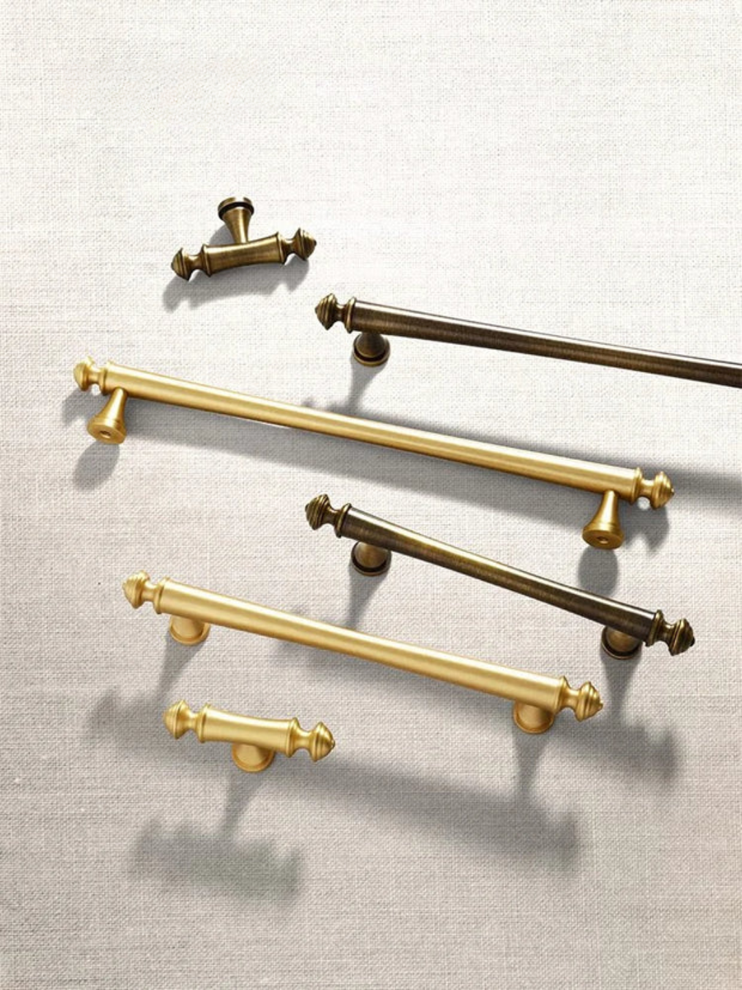 Set of gold and bronze cabinet handles on a light gray background