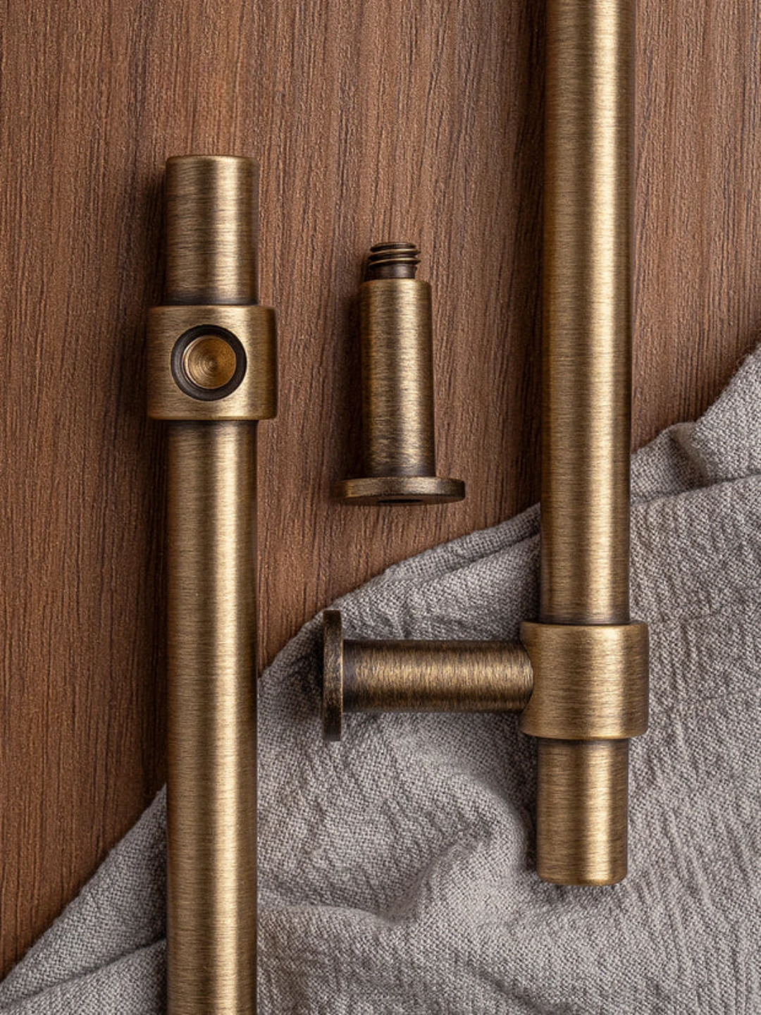 Brass curtain rods on a wooden surface with a gray fabric background