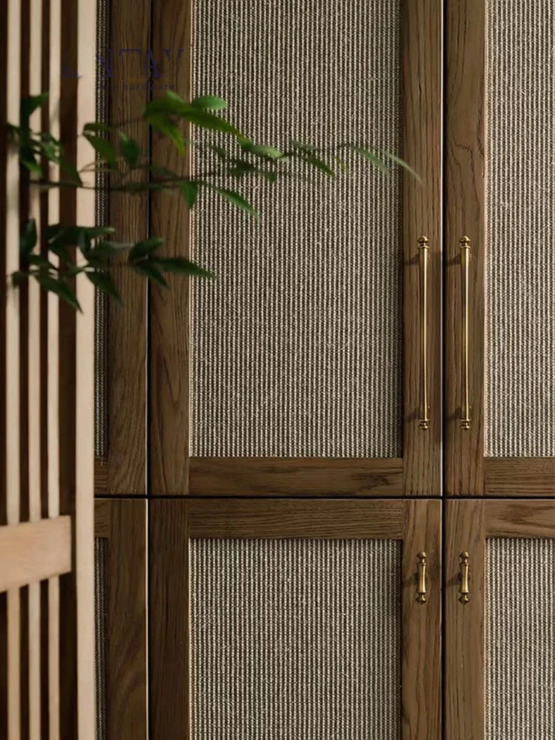 Wooden cabinet with textured glass panels and gold handles, featuring a plant in the foreground.