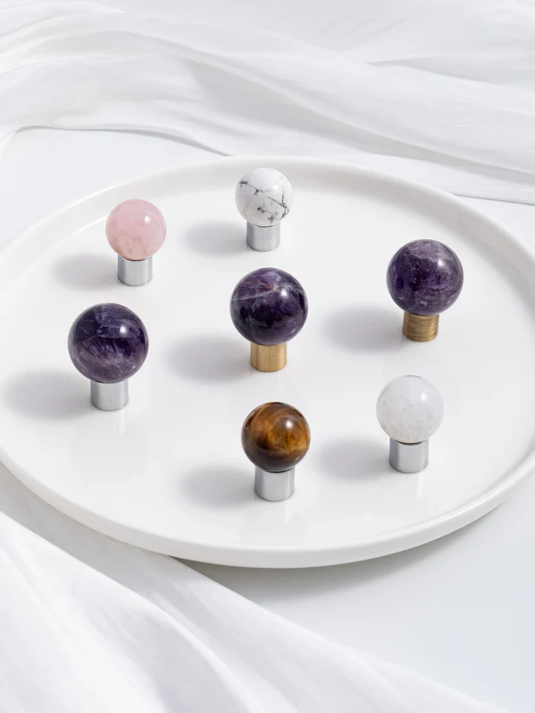 Set of colorful stone knobs on a white plate with a white fabric background
