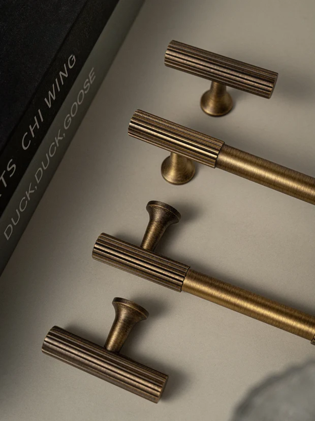 Bronze cabinet handles on a neutral background with 'Duck Duck Goose' branding.