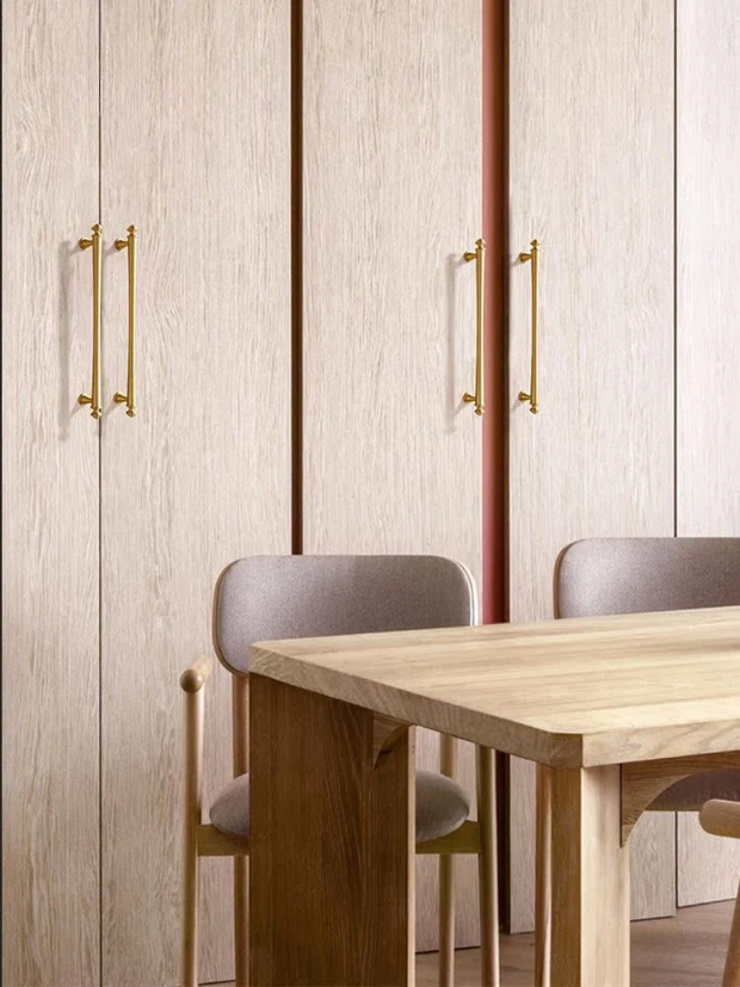 Dining area with wooden table and chairs against a paneled wall.