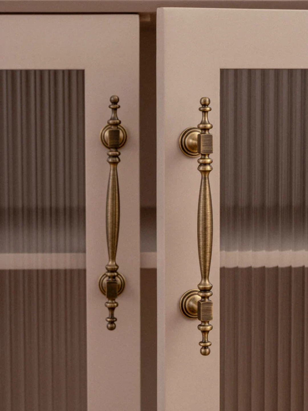 Close-up of a pair of glass doors with ornate brass handles.