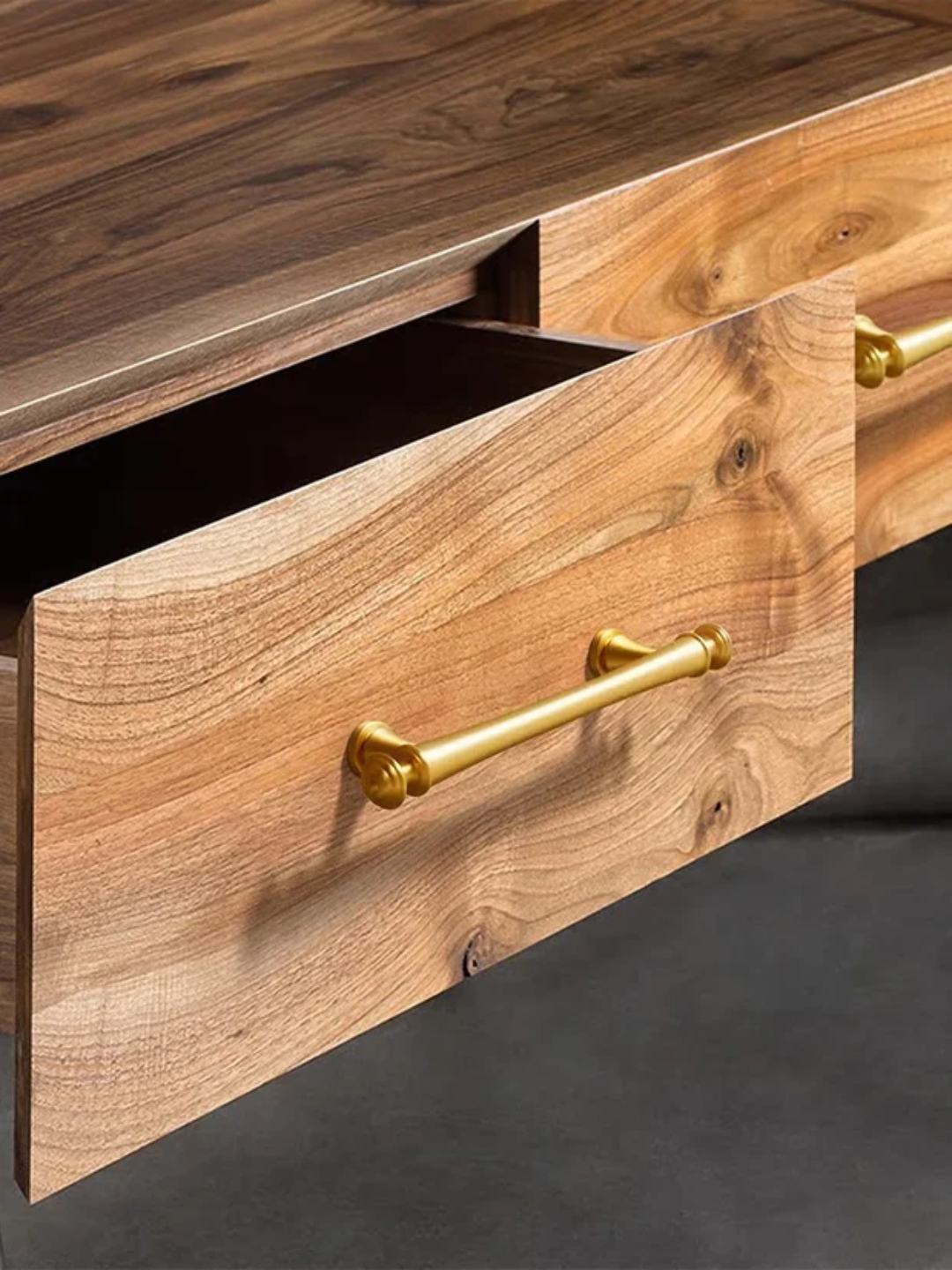 Wooden drawer with gold handles on a dark background.