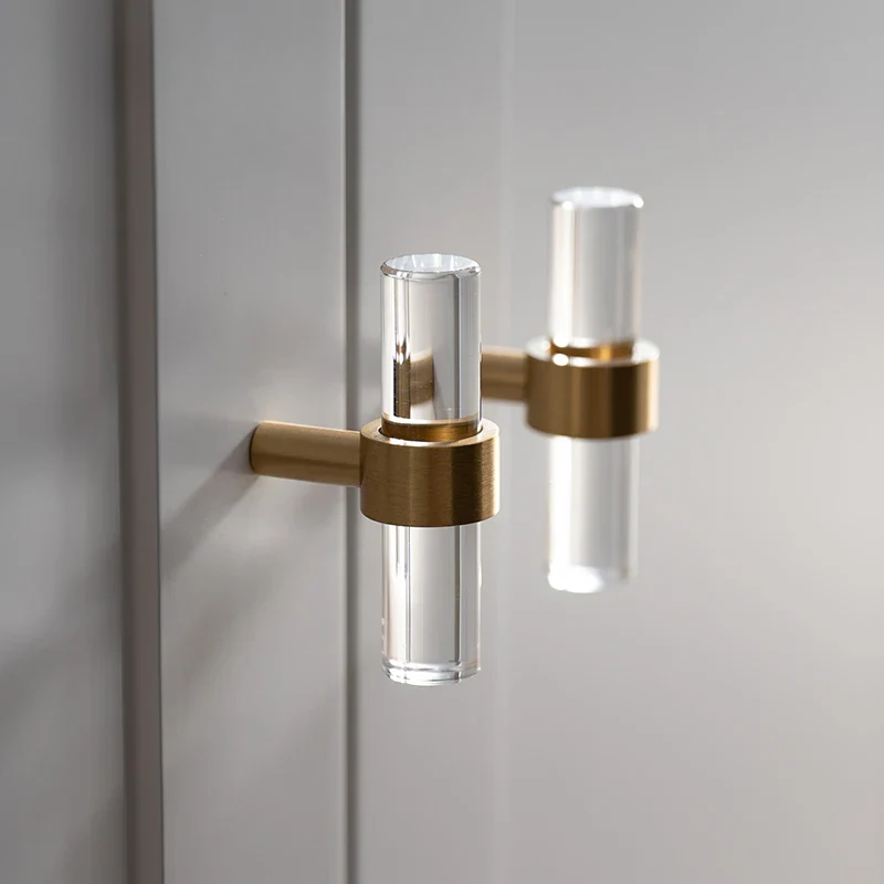 Modern door handle with clear acrylic and gold finish on a gray door.