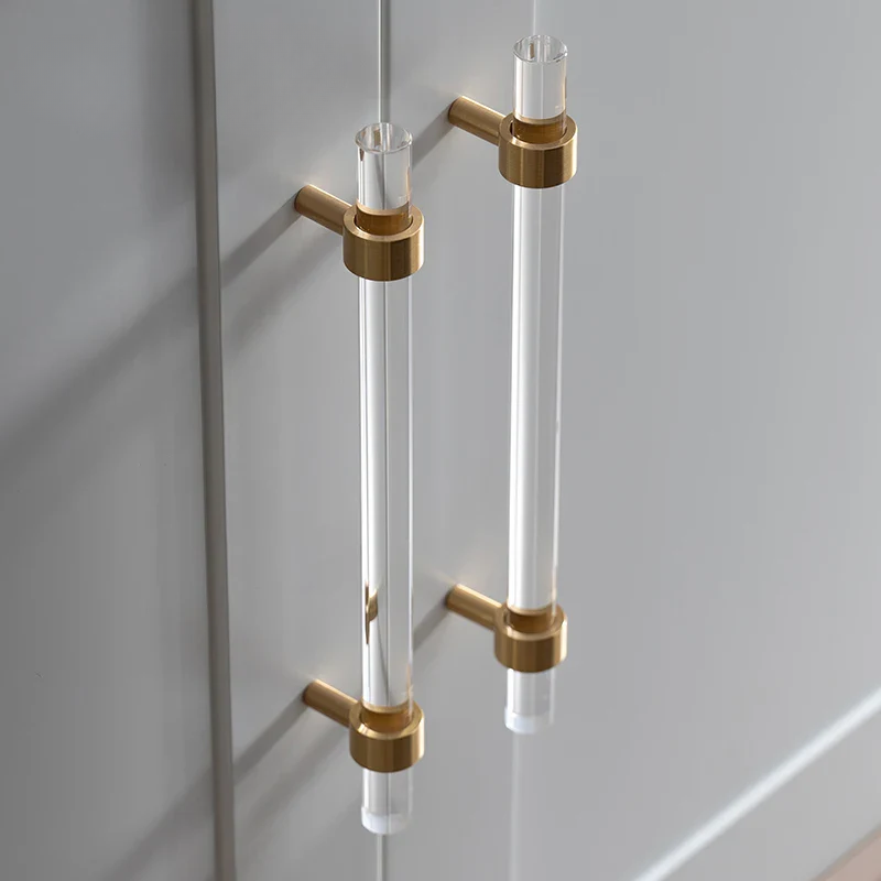 Clear acrylic handles with gold accents on a glass door