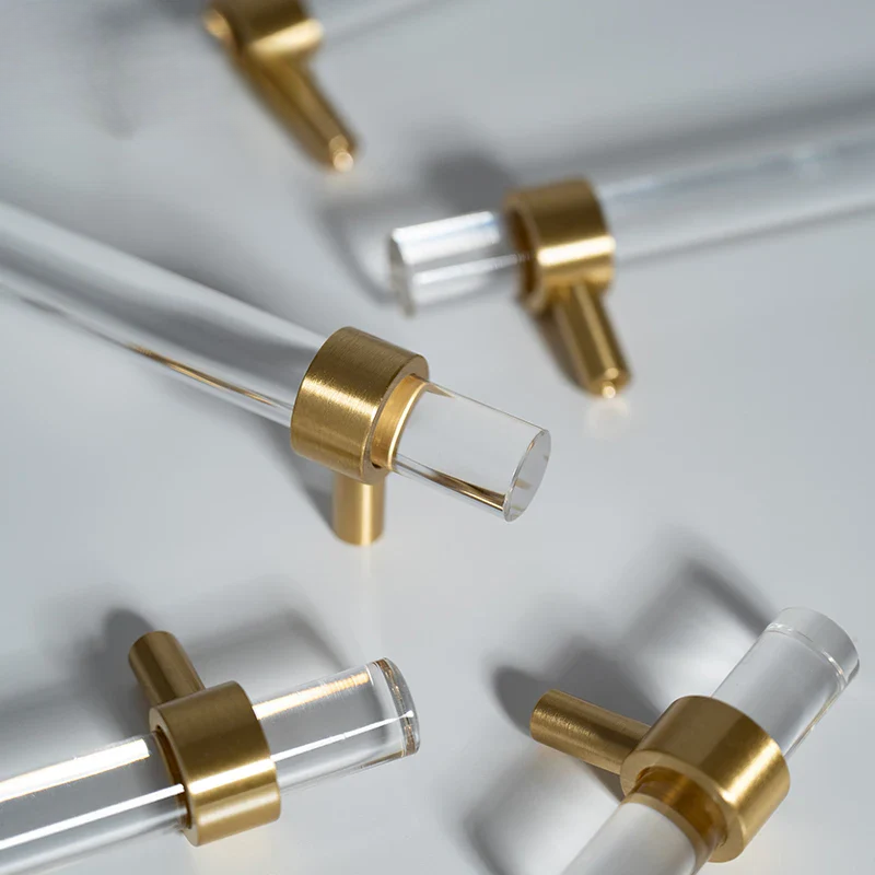 Gold and clear acrylic drawer pulls on a white background