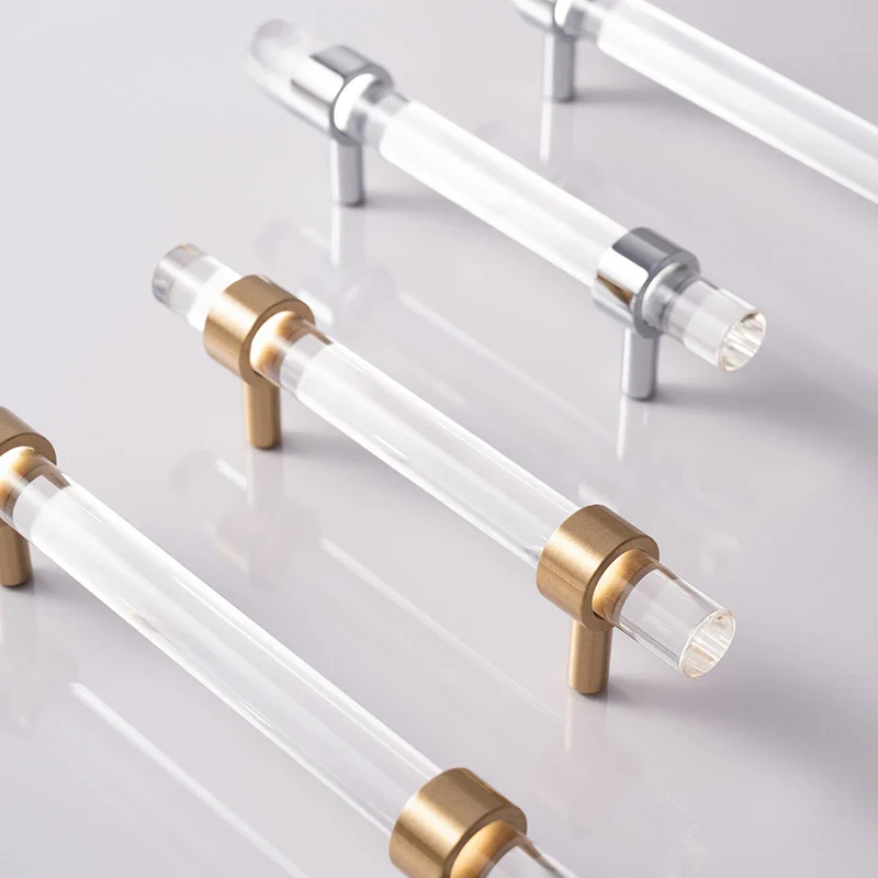 Clear acrylic cabinet handles with metallic ends on a light gray background