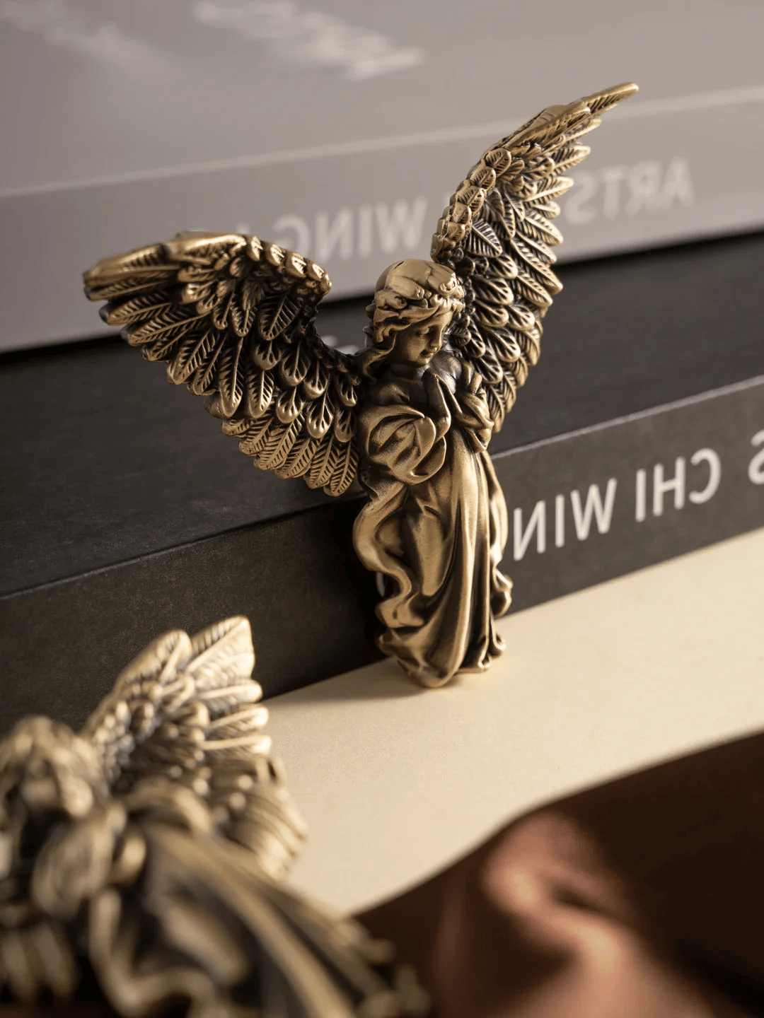 Bronze angel figurine on a reflective surface with a blurred background
