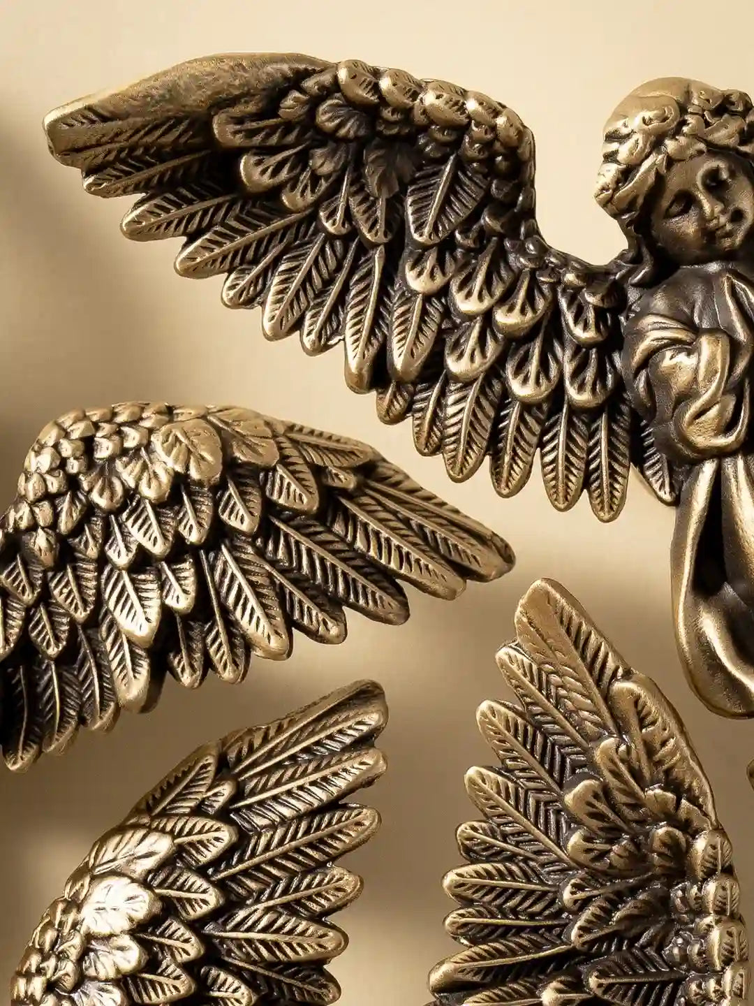 Bronze angel figurine with detailed wings on a gold background