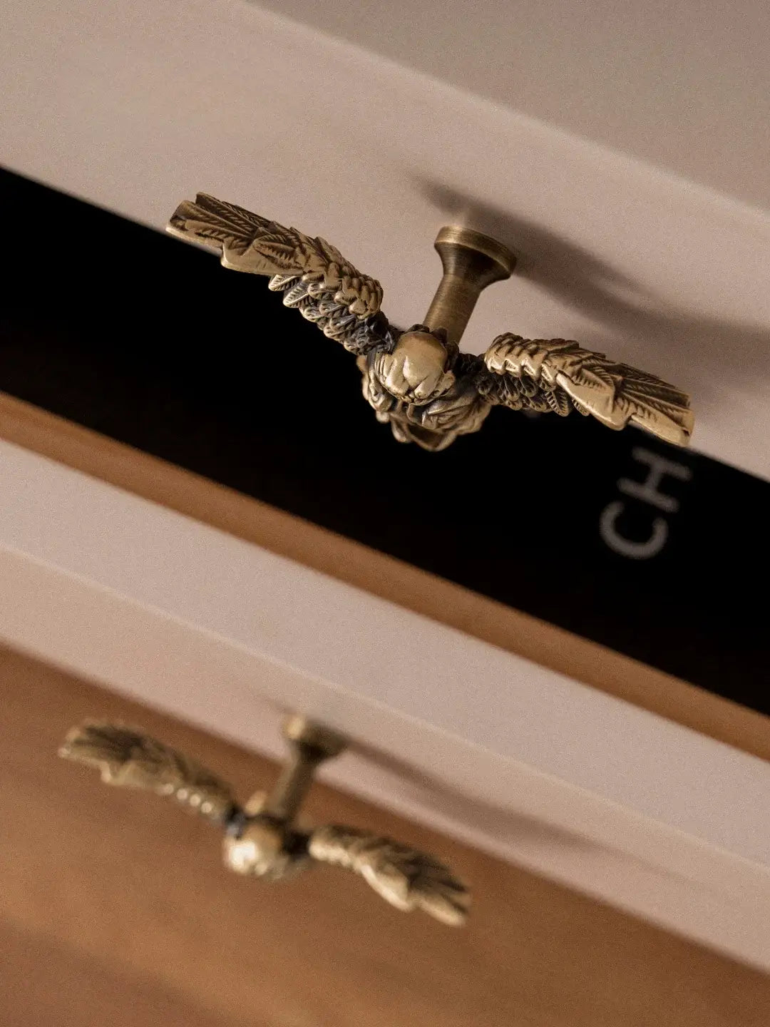 Close-up of ornate brass handles on a wooden cabinet.