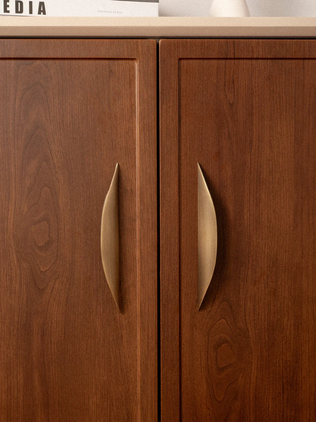 Wooden cabinet doors with metallic handles on a light-colored countertop.