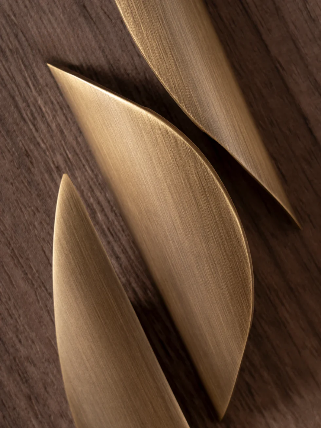 Close-up of three gold leaf-shaped objects on a wooden surface