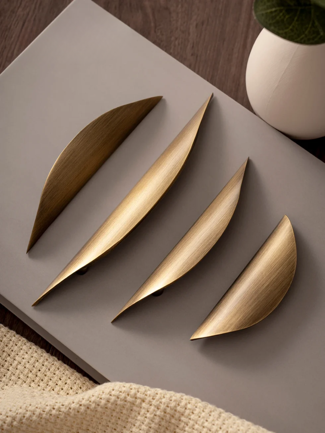 Gold leaf-shaped decorative items on a gray surface with a plant in the background