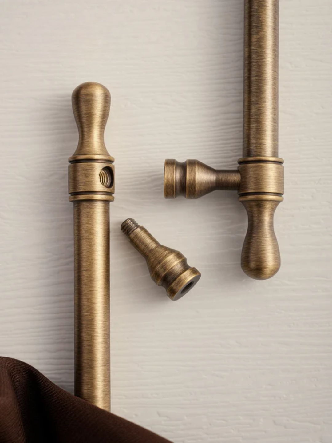 Brass curtain rods and hardware on a textured beige background