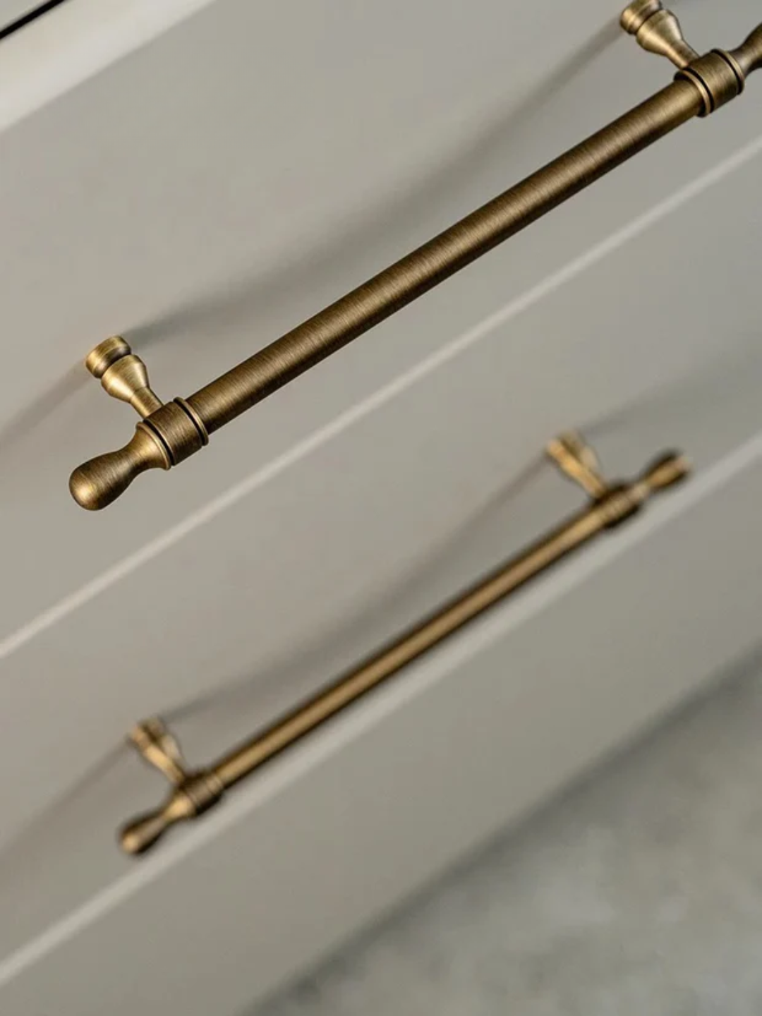 Close-up of gold cabinet handles on a light gray cabinet.