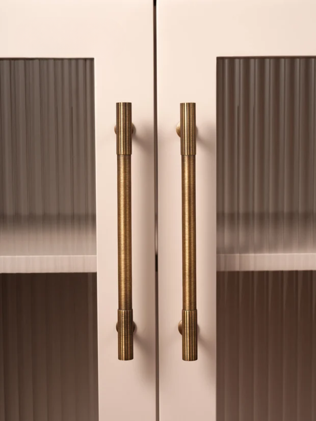 Cabinet doors with bronze handles on a light pink background