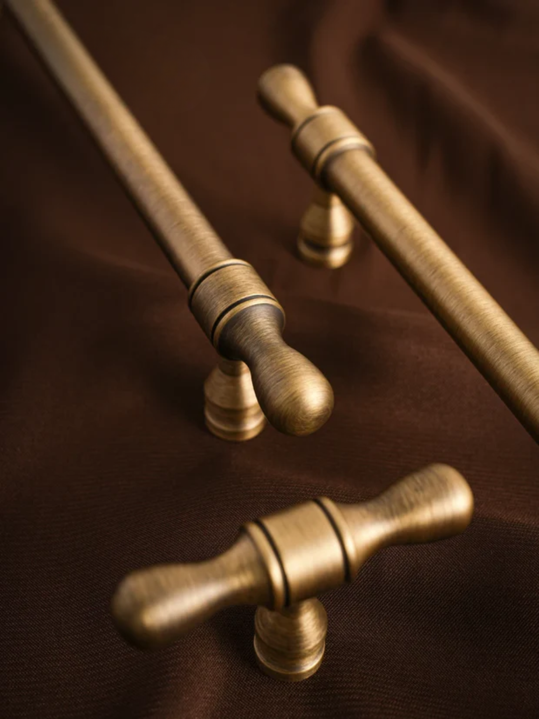 Set of gold cabinet handles on a brown fabric background