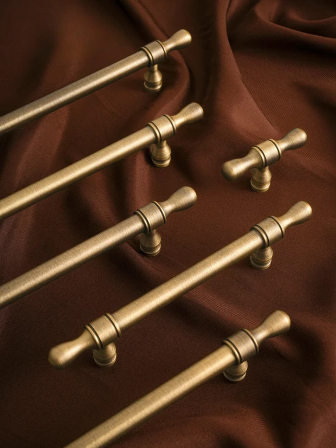 Set of gold cabinet handles on a brown fabric background