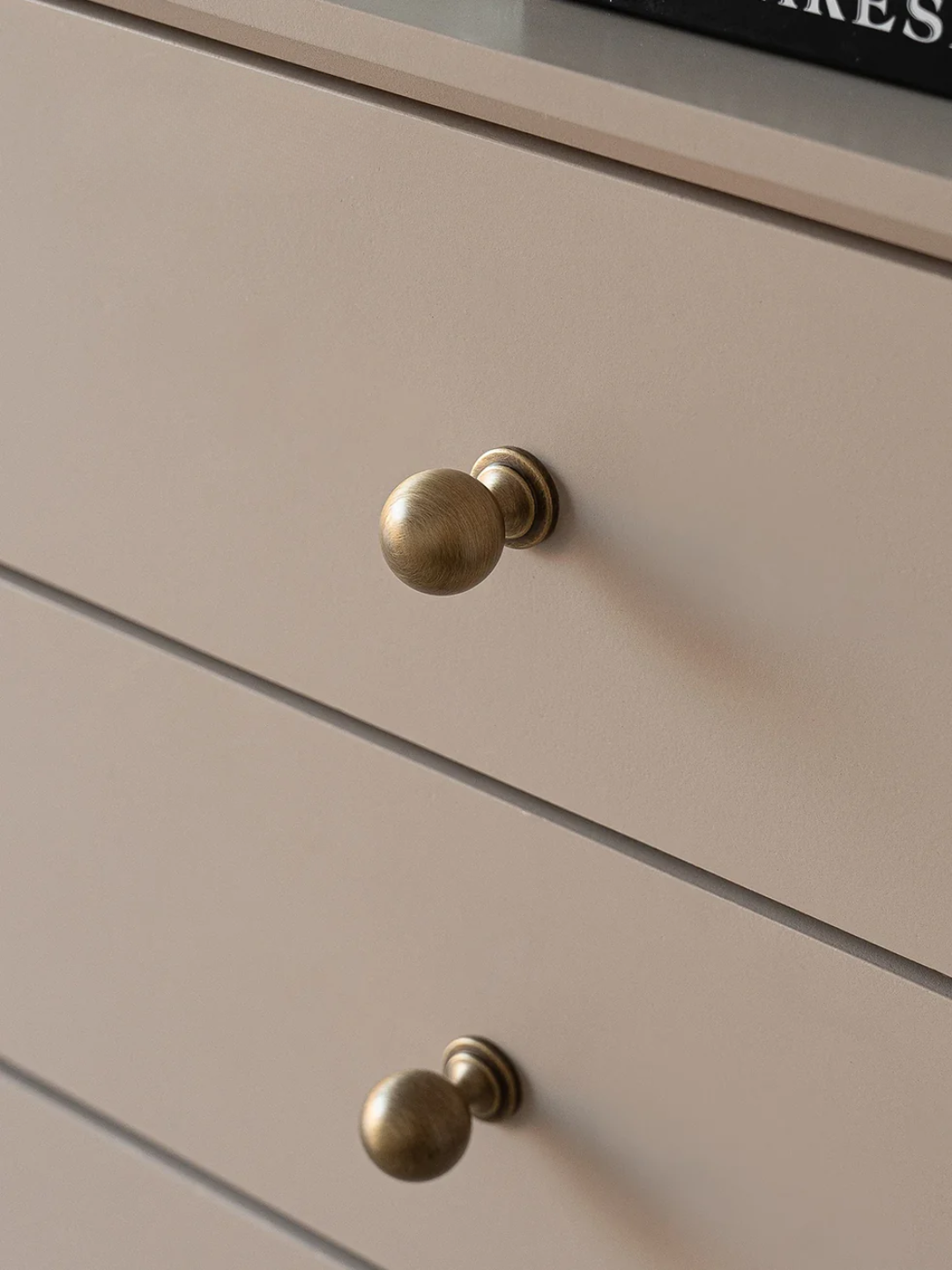 Close-up of a beige drawer with brass knobs
