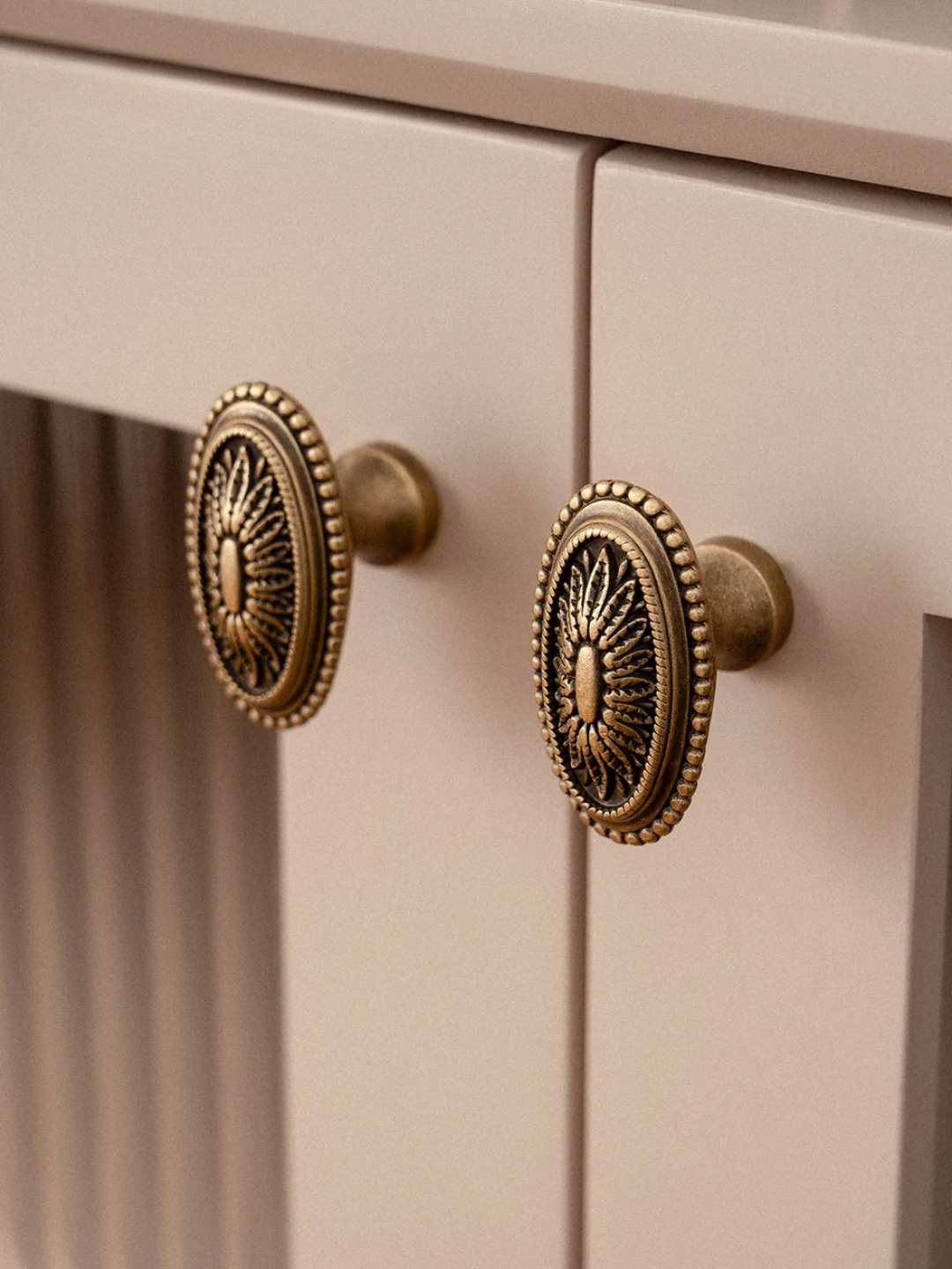 Close-up of beige cabinet with decorative bronze handles