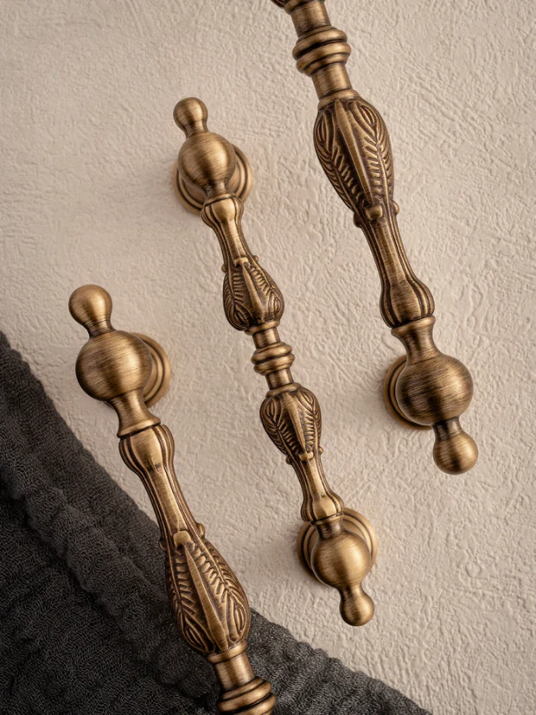 Two ornate bronze handles on a textured wall.
