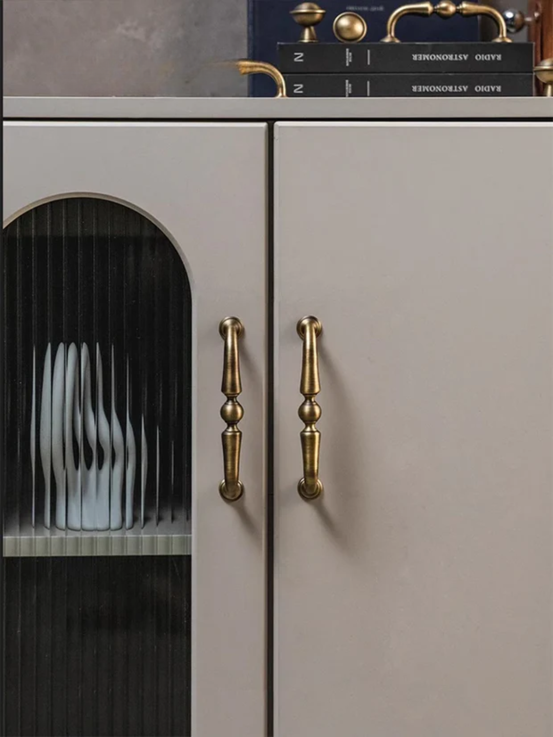 Cabinet with gold handles and a dish rack inside, on a dark surface.