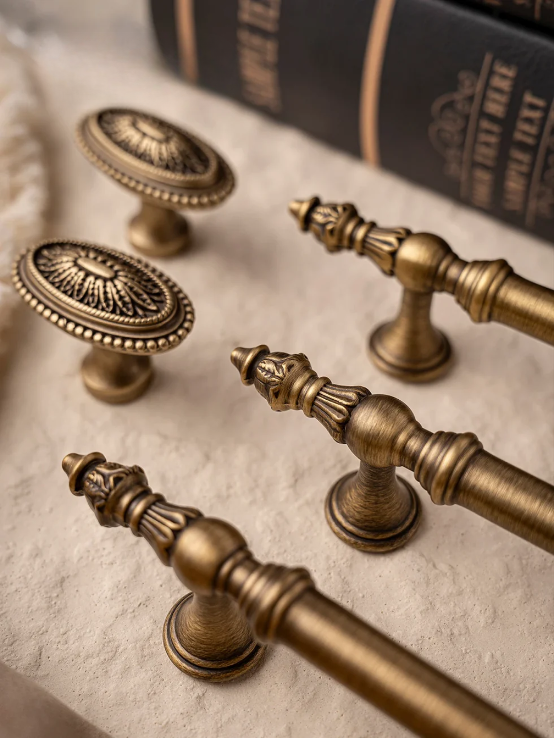 Collection of vintage-style brass cabinet handles on a textured surface.