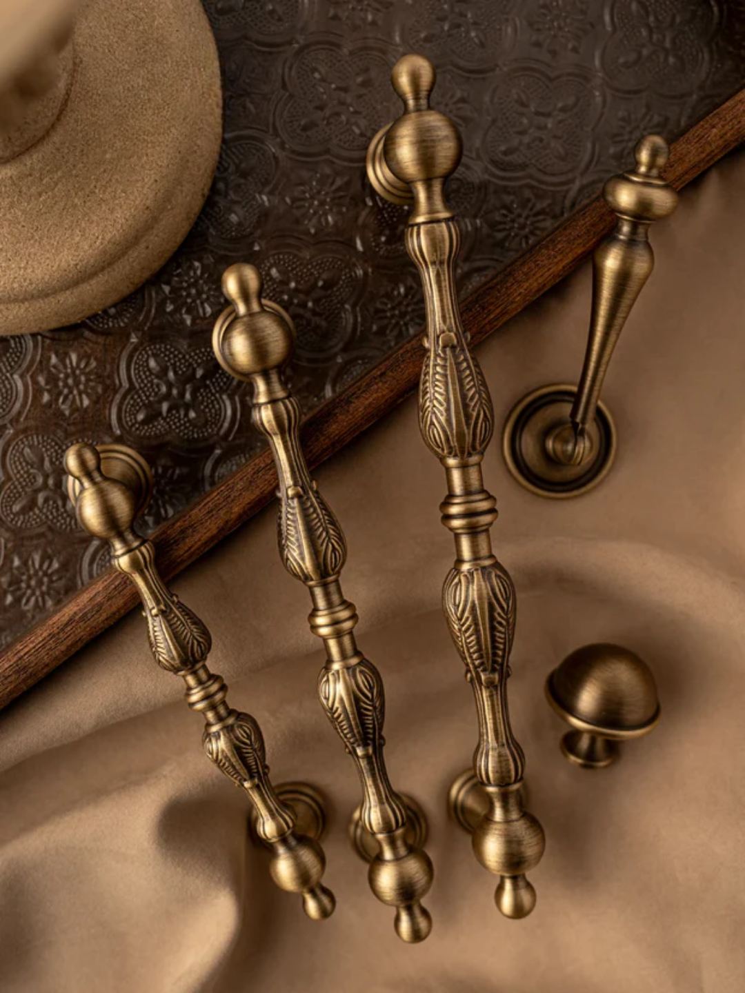Set of ornate brass cabinet handles on a textured surface