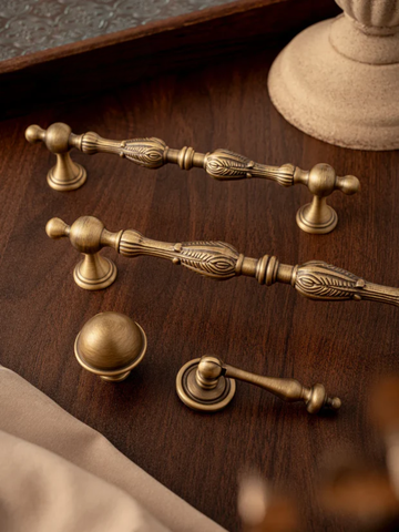 Set of vintage-style brass cabinet handles on a wooden surface