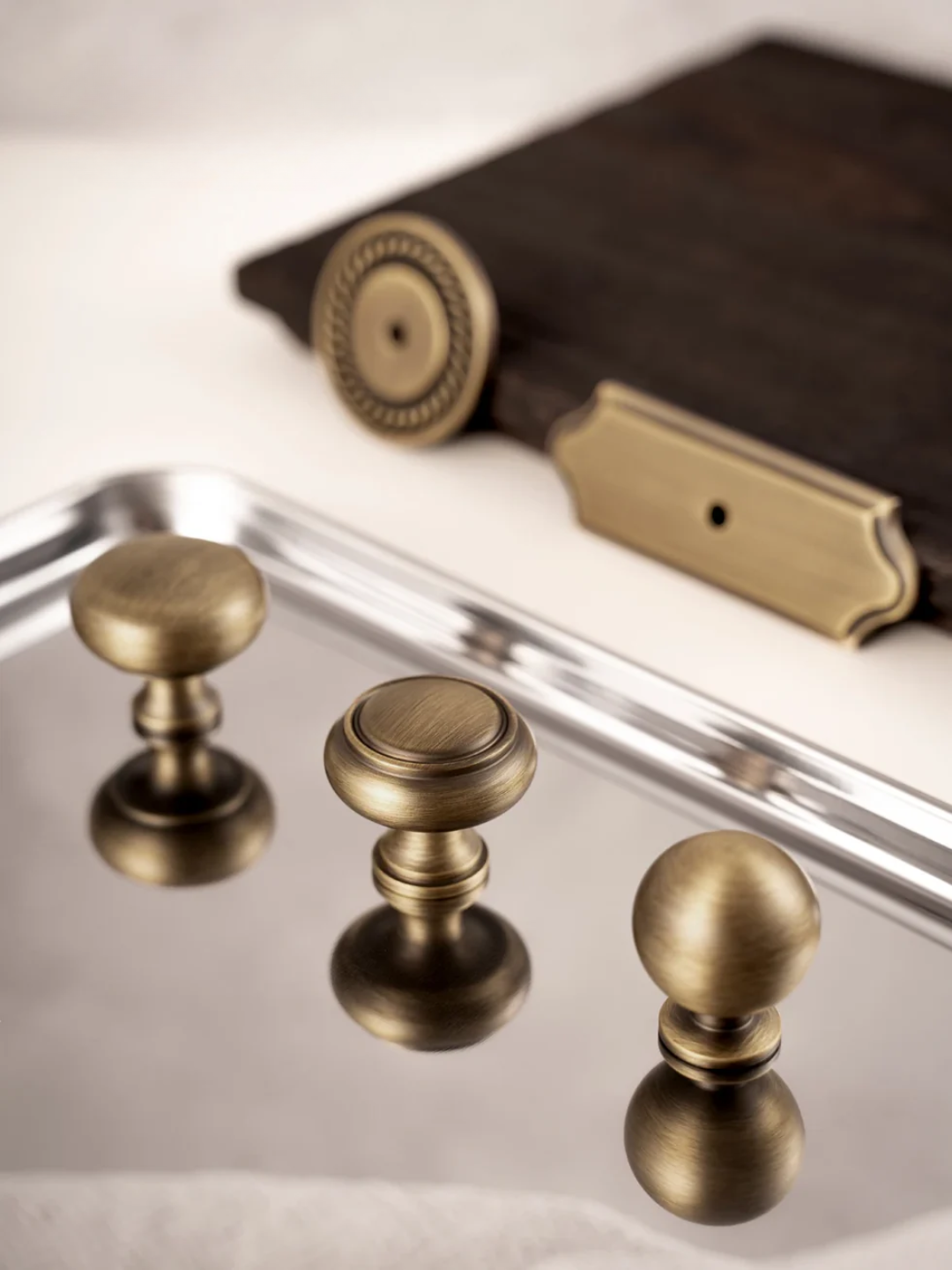 Three brass cabinet knobs on a reflective surface with a blurred background