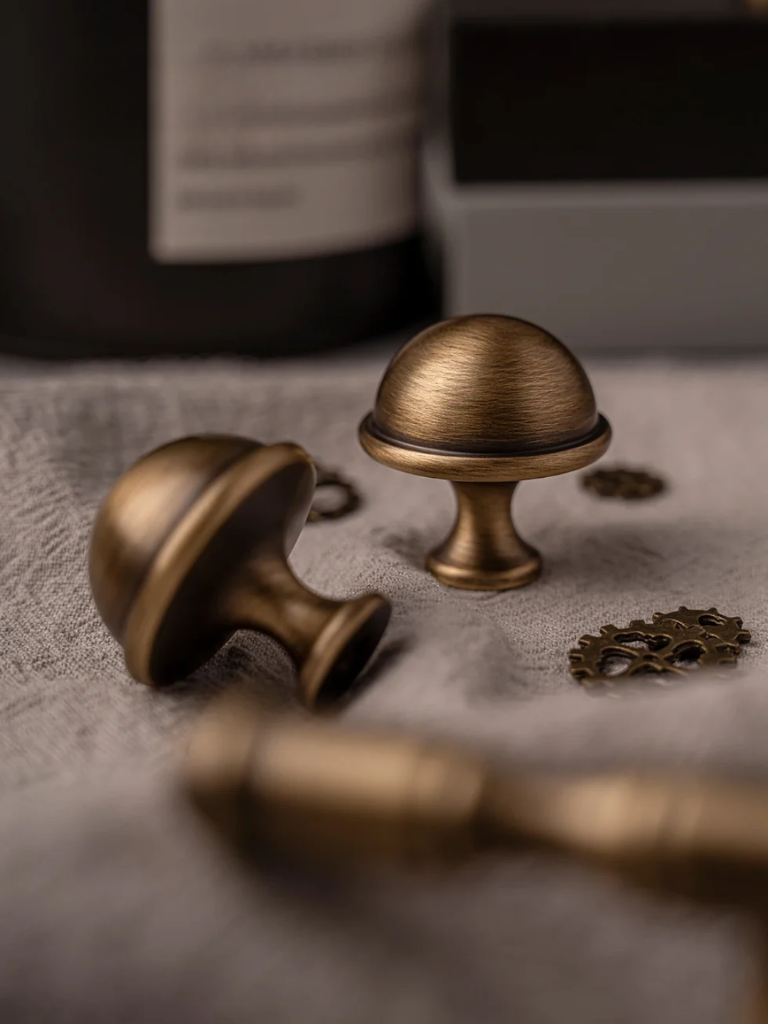 Bronze cabinet knobs on a textured surface with a blurred background