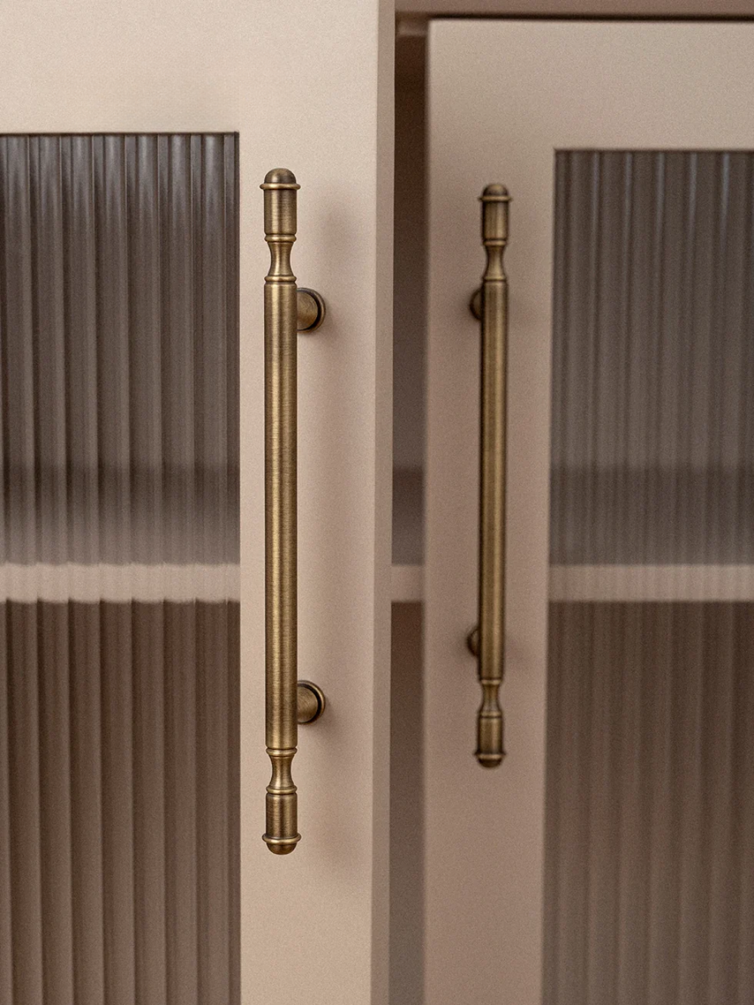 Close-up of bronze cabinet handles on a glass-paneled door.